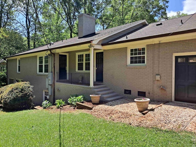 view of front of property featuring a chimney, brick siding, a porch, and a front lawn