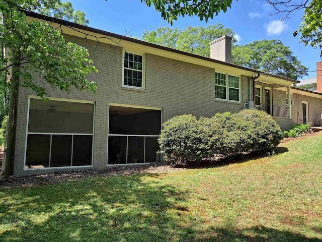 rear view of house with a yard, a chimney, and brick siding