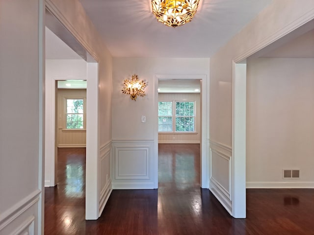 corridor with a wealth of natural light, a notable chandelier, and a decorative wall