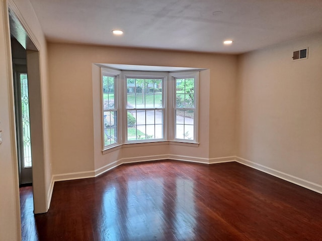 unfurnished room featuring dark wood-type flooring, visible vents, recessed lighting, and baseboards