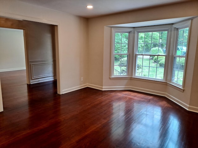 spare room featuring dark wood-type flooring, recessed lighting, a wealth of natural light, and baseboards