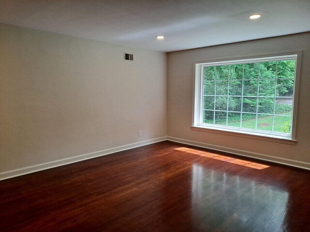 empty room featuring dark wood-type flooring, recessed lighting, visible vents, and baseboards
