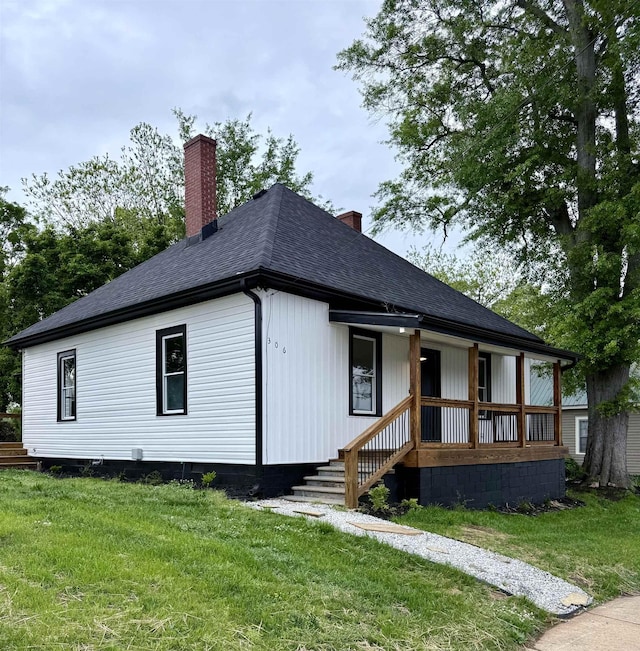 view of front of property featuring a chimney, a porch, and a front lawn