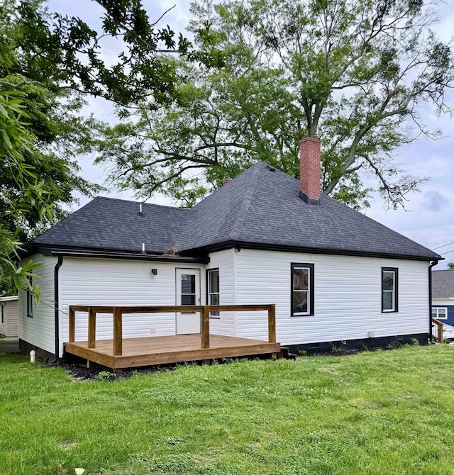 rear view of house featuring a deck, a yard, roof with shingles, and a chimney