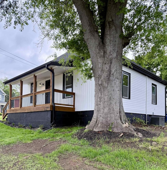 view of side of property with covered porch and central AC