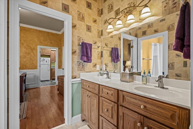 full bathroom featuring wainscoting, ornamental molding, double vanity, and a sink
