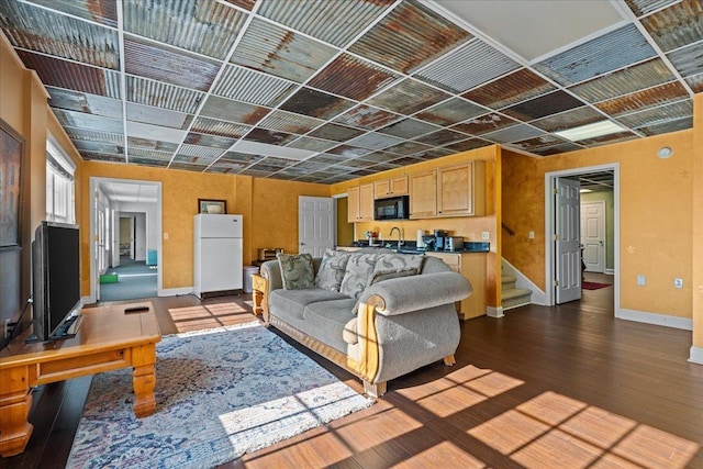living room featuring dark wood-type flooring, stairs, and baseboards