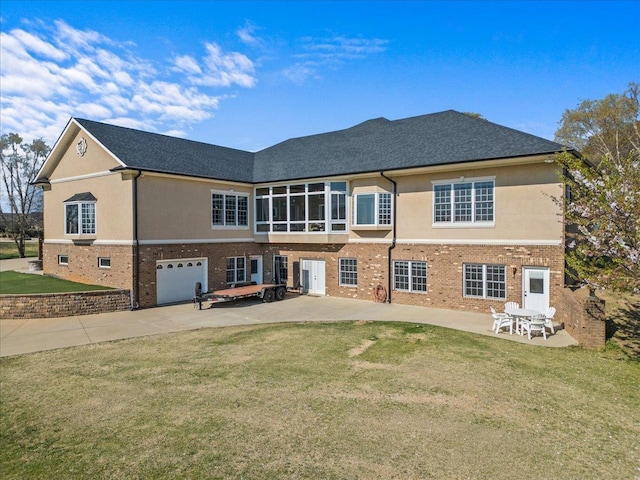 back of house featuring a lawn, brick siding, concrete driveway, and a patio area