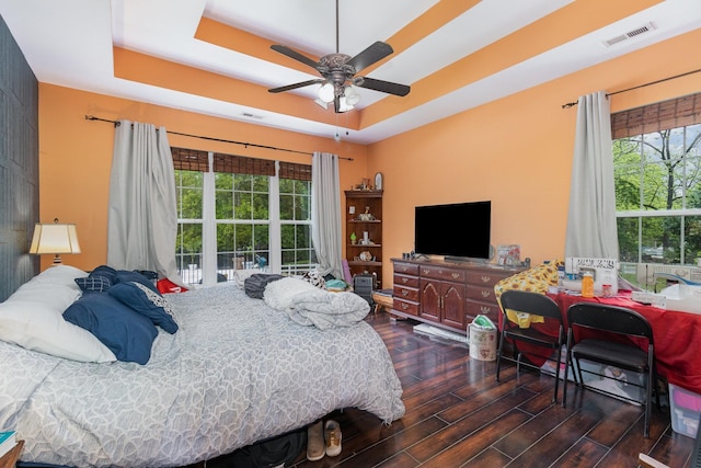 bedroom with visible vents, wood finished floors, ceiling fan, and a tray ceiling