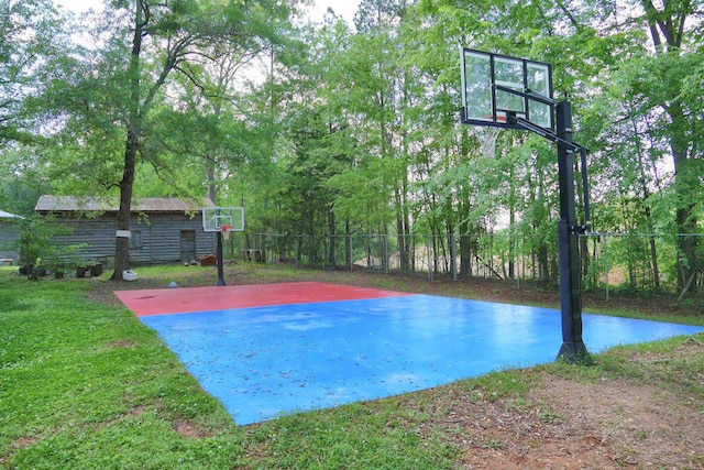 view of basketball court featuring fence and basketball hoop
