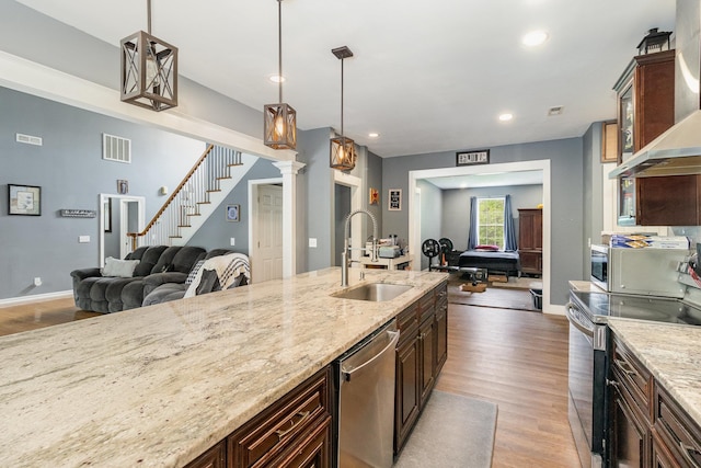 kitchen with open floor plan, a sink, stainless steel appliances, and light wood-style floors
