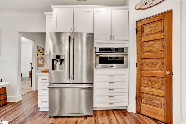 kitchen featuring white cabinets, appliances with stainless steel finishes, and light wood-type flooring