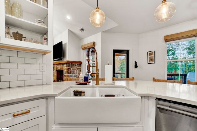 kitchen with tasteful backsplash, decorative light fixtures, dishwasher, a sink, and visible vents