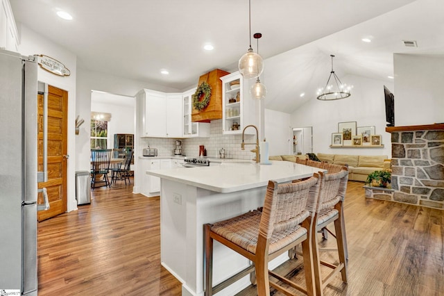 kitchen with light wood-style flooring, freestanding refrigerator, a chandelier, a kitchen bar, and a sink