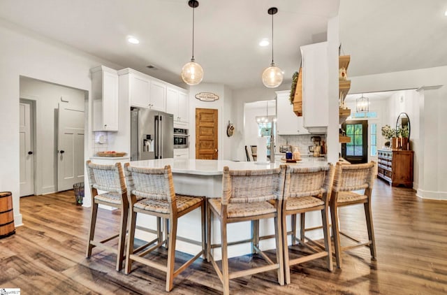 kitchen featuring decorative backsplash, stainless steel appliances, light countertops, white cabinets, and a peninsula