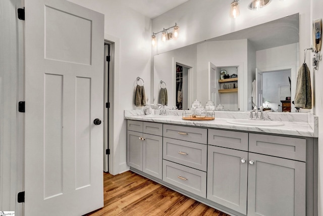 bathroom with double vanity, a sink, and wood finished floors