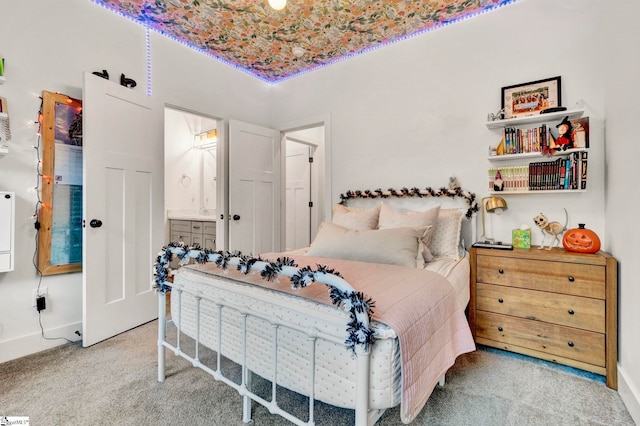 carpeted bedroom featuring ensuite bath and baseboards