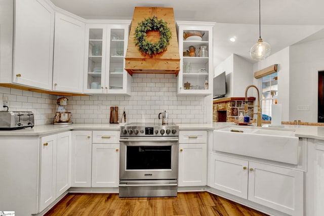 kitchen with a sink, stainless steel range with electric cooktop, light wood-style flooring, light countertops, and white cabinets