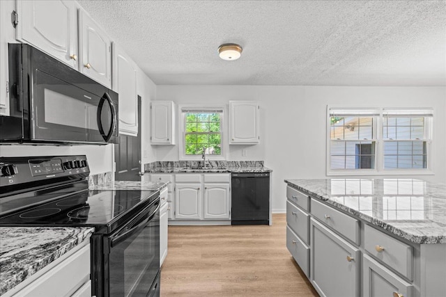 kitchen featuring light stone countertops, a sink, black appliances, white cabinetry, and a textured ceiling