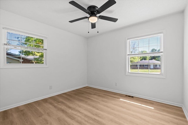 spare room with light wood finished floors, visible vents, ceiling fan, and baseboards