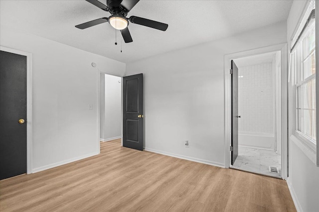 unfurnished bedroom featuring ceiling fan, light wood-type flooring, ensuite bath, and baseboards