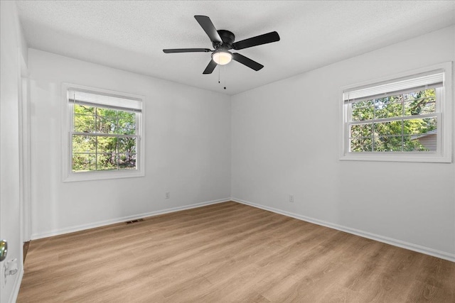 spare room with a ceiling fan, visible vents, light wood-style flooring, and baseboards