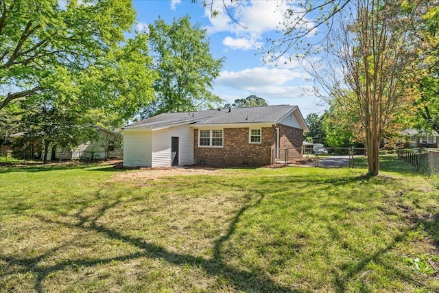 rear view of property with brick siding, a fenced backyard, a yard, and crawl space