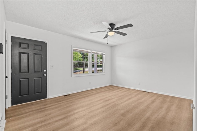 interior space featuring light wood finished floors, ceiling fan, visible vents, baseboards, and a textured ceiling