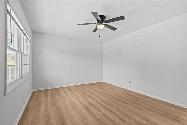 unfurnished room featuring baseboards, light wood-style floors, a ceiling fan, and a textured ceiling