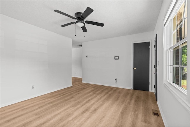 spare room featuring baseboards, visible vents, ceiling fan, and light wood finished floors