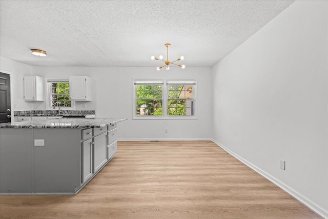 kitchen with a wealth of natural light, a textured ceiling, and light wood-style flooring