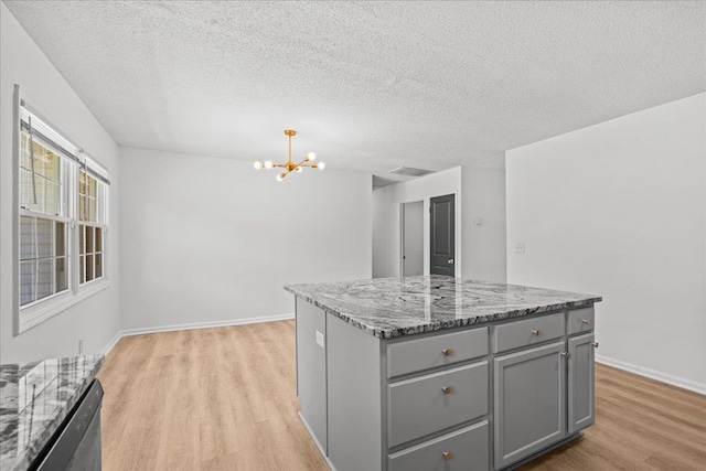 kitchen with an inviting chandelier, light wood-type flooring, visible vents, light stone counters, and gray cabinetry