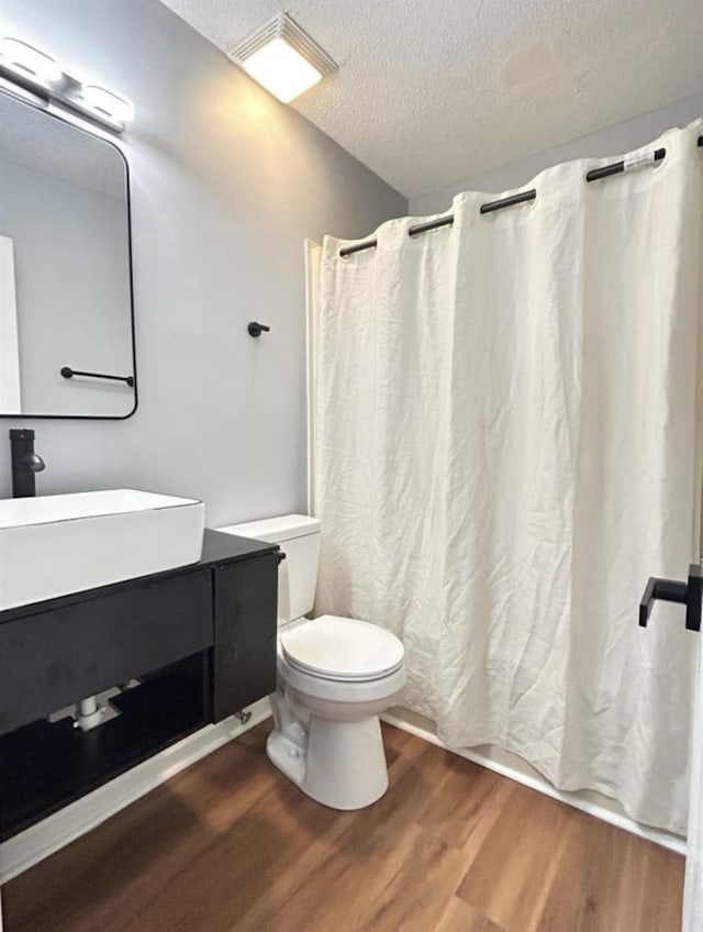 bathroom featuring wood finished floors, toilet, a textured ceiling, and vanity