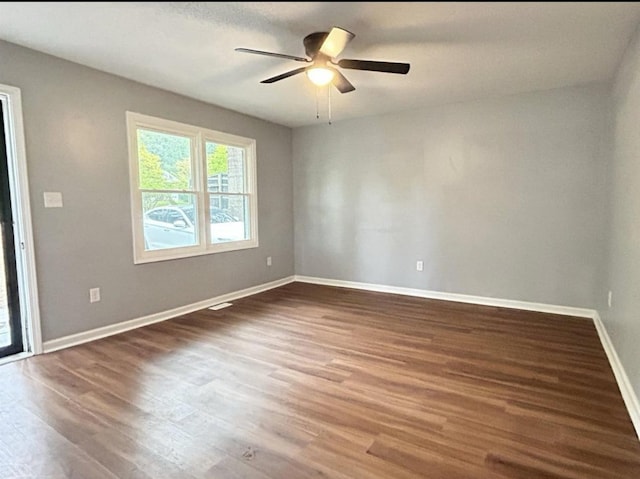 spare room featuring baseboards, ceiling fan, and dark wood-style flooring