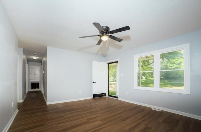 spare room featuring dark wood-type flooring, visible vents, ceiling fan, and baseboards