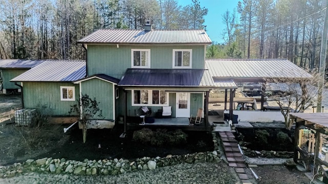 rear view of house featuring metal roof and a chimney