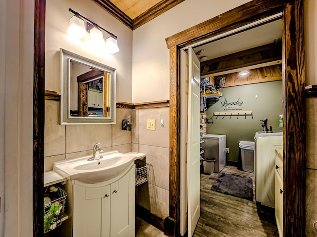 bathroom featuring crown molding, washer and dryer, tile walls, wood finished floors, and vanity