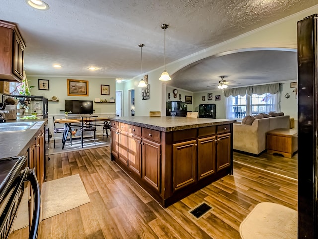 kitchen featuring a sink, stove, a ceiling fan, a textured ceiling, and open floor plan
