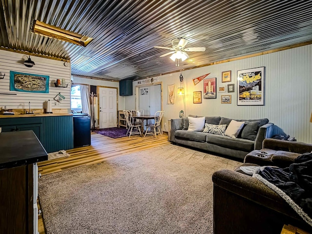 living room featuring ceiling fan, wood walls, and wood finished floors