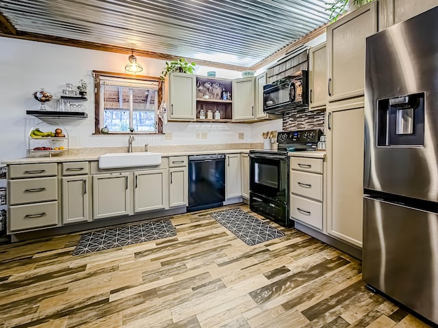 kitchen with a sink, light wood-style floors, open shelves, black appliances, and light countertops
