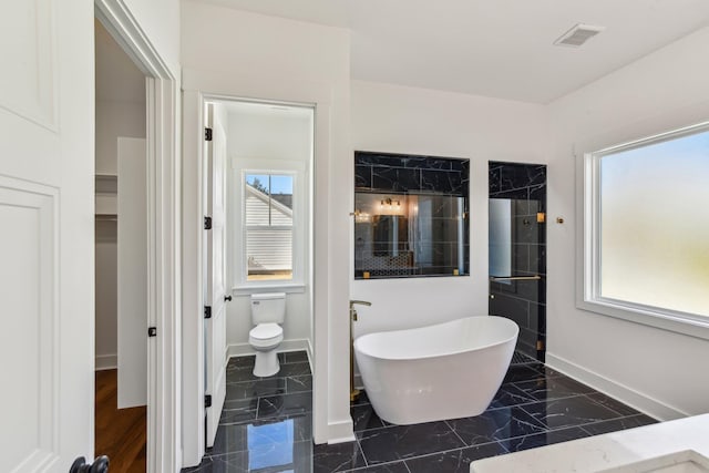 full bathroom with tiled shower, marble finish floor, a freestanding tub, toilet, and baseboards