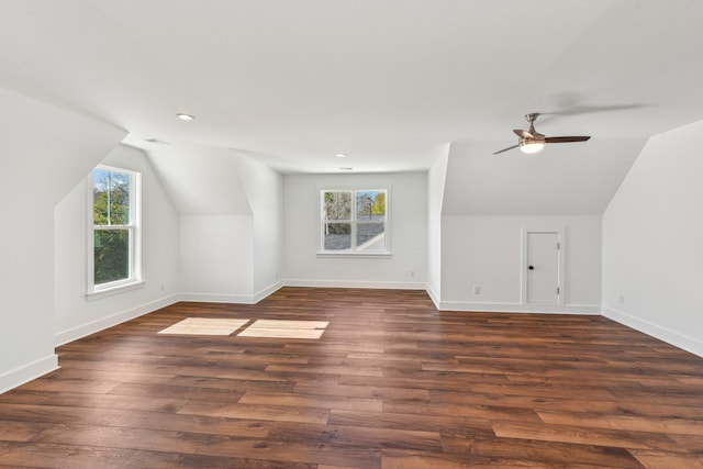 additional living space with dark wood-style flooring, a wealth of natural light, vaulted ceiling, and baseboards