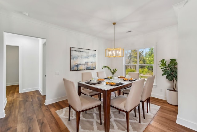 dining room with baseboards, wood finished floors, an inviting chandelier, and ornamental molding