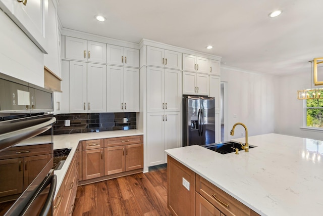 kitchen with recessed lighting, a sink, dark wood-style flooring, stainless steel appliances, and light stone counters