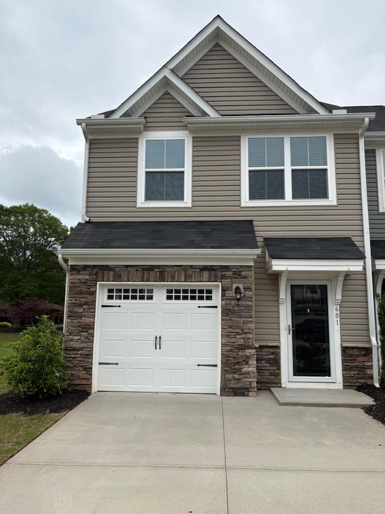 view of front of home featuring an attached garage, driveway, and stone siding