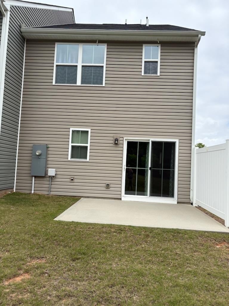 rear view of house featuring a yard, fence, and a patio area