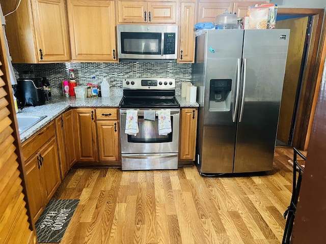 209 Demos, Roebuck, SC 29376 - kitchen featuring appliances with stainless steel finishes, backsplash, light wood-type flooring, and light stone counters