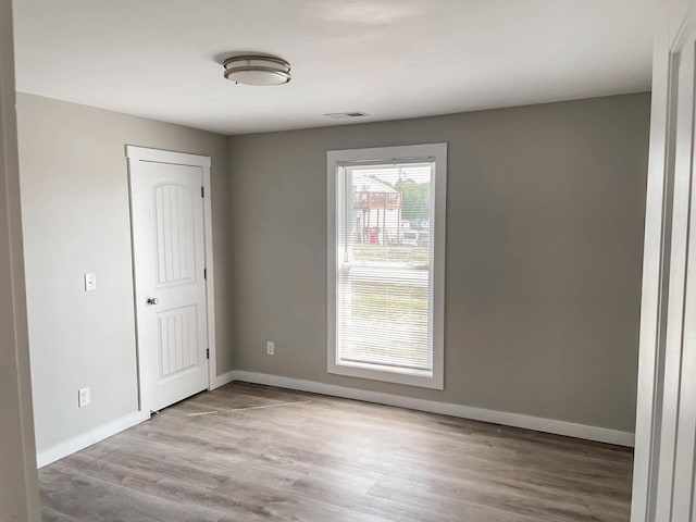 empty room featuring baseboards, wood finished floors, and visible vents