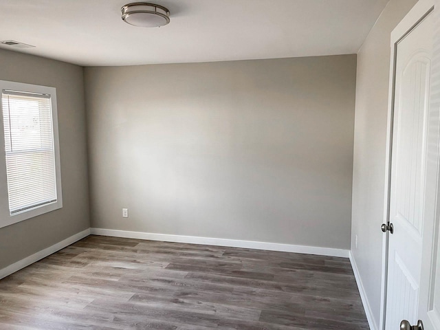spare room with baseboards, wood finished floors, and visible vents