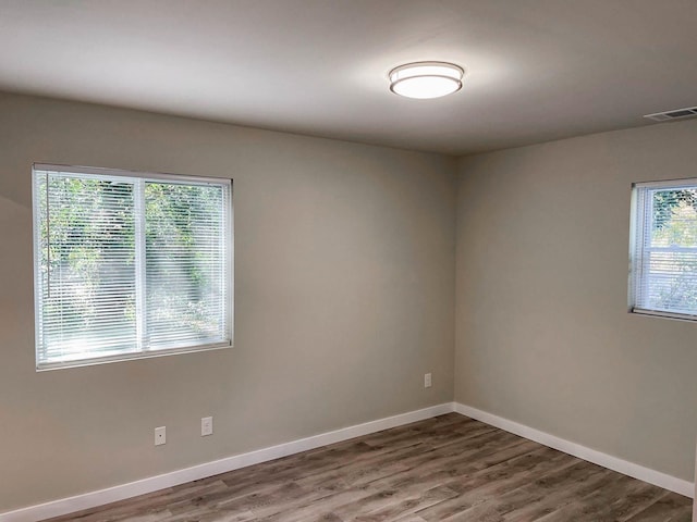 unfurnished room with baseboards, wood finished floors, and visible vents